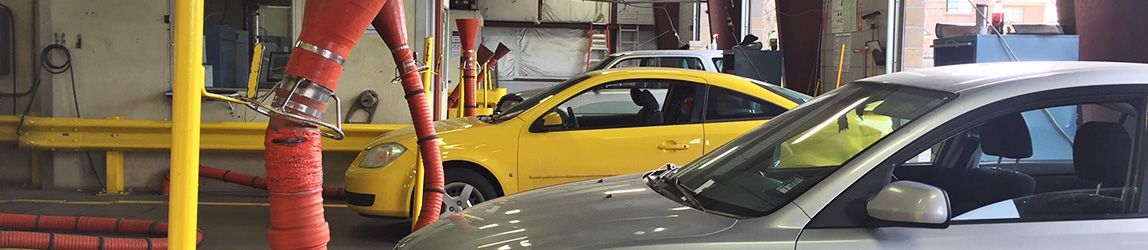 Two cars inside an Aircare Colorado emissions testing facility